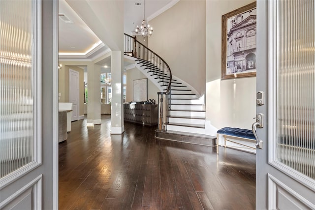 entryway with crown molding, dark wood-type flooring, and a notable chandelier