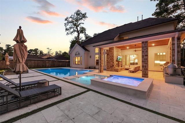 pool at dusk with an in ground hot tub, an outdoor hangout area, area for grilling, ceiling fan, and a patio area