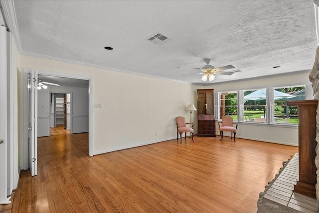 unfurnished room with a textured ceiling, light wood finished floors, a ceiling fan, and crown molding