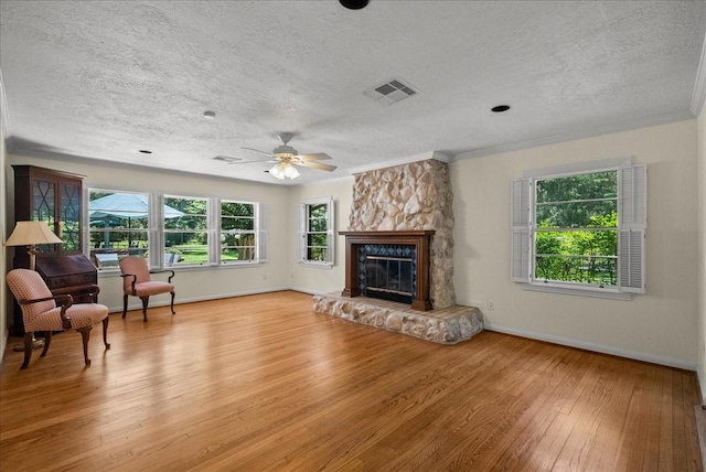 living area featuring a fireplace, visible vents, ornamental molding, light wood-type flooring, and baseboards