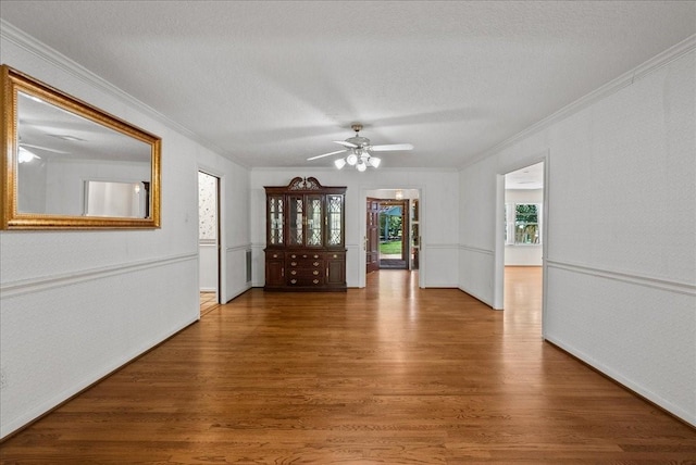 spare room with a textured ceiling, ornamental molding, wood finished floors, and a ceiling fan