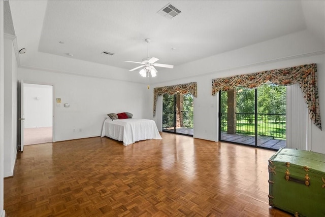 unfurnished bedroom featuring access to outside, a tray ceiling, visible vents, and a ceiling fan