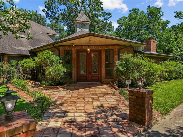 entrance to property with french doors, brick siding, and a chimney