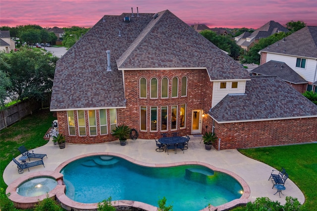 pool at dusk featuring an in ground hot tub and a patio