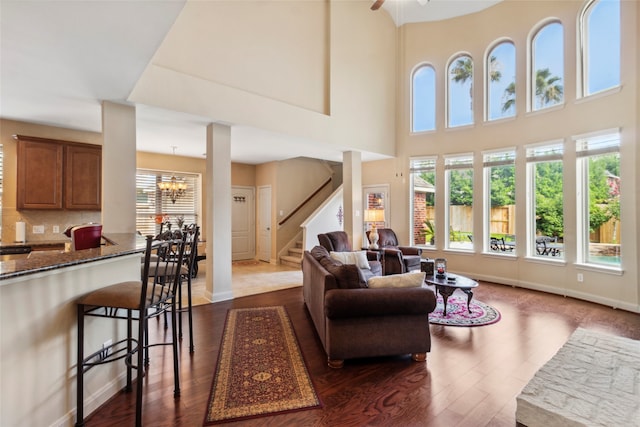 living room with dark wood-type flooring, a high ceiling, and a notable chandelier