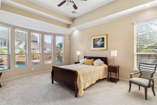 bedroom with a tray ceiling, ceiling fan, light carpet, and ornamental molding