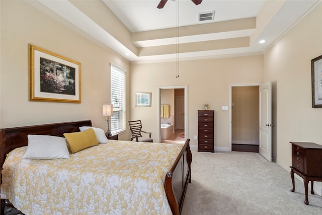 bedroom with connected bathroom, ceiling fan, light colored carpet, a tray ceiling, and ornamental molding