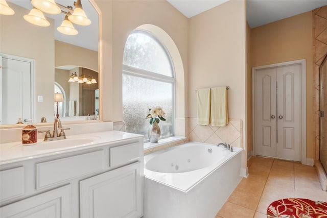 bathroom featuring tile patterned flooring, a washtub, vanity, and an inviting chandelier