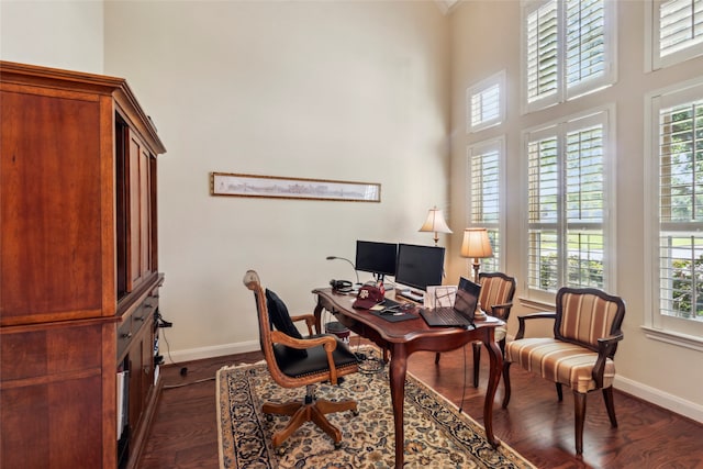 home office featuring a healthy amount of sunlight, dark hardwood / wood-style flooring, and a towering ceiling