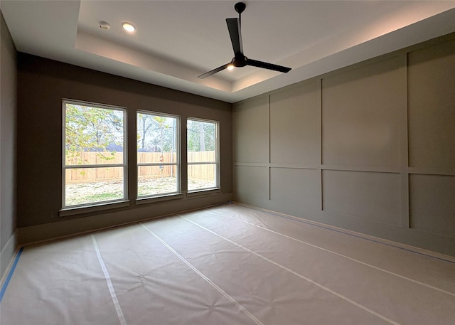 spare room featuring ceiling fan and a raised ceiling