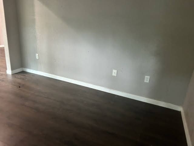 unfurnished room with dark hardwood / wood-style flooring