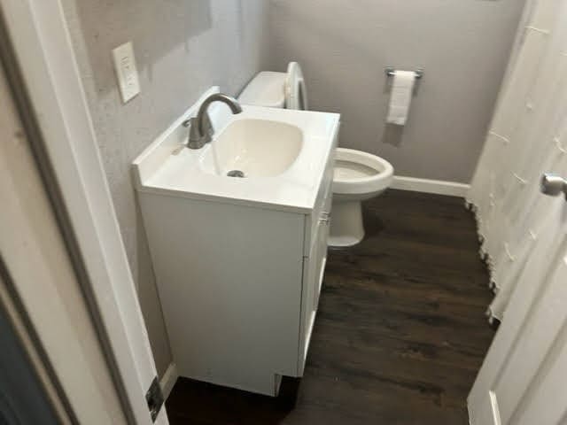 bathroom featuring wood-type flooring, toilet, and vanity