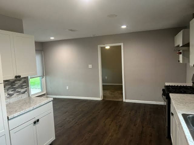 kitchen featuring white cabinetry, stainless steel gas range, and dark hardwood / wood-style flooring