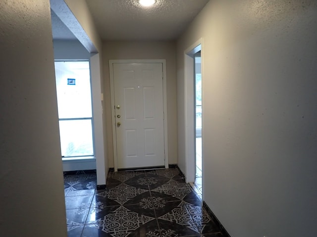 interior space featuring a textured ceiling and dark tile floors