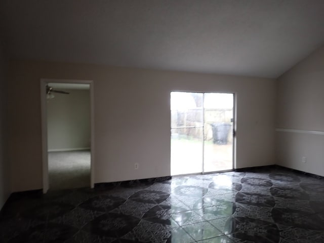 unfurnished room with lofted ceiling and dark tile floors