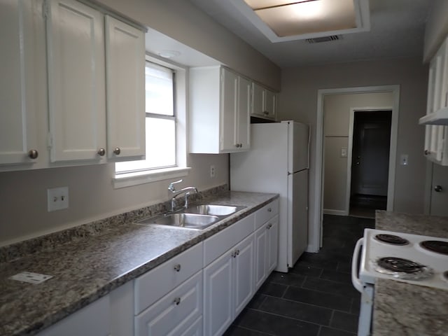 kitchen with white cabinets, sink, dark tile flooring, and range