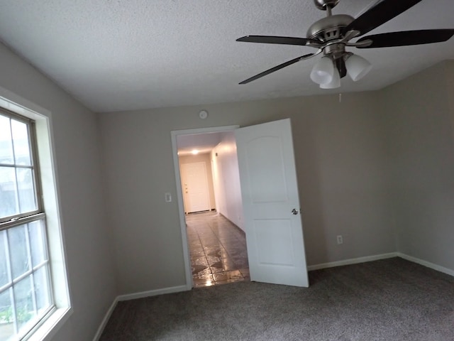 carpeted spare room with a textured ceiling, plenty of natural light, and ceiling fan