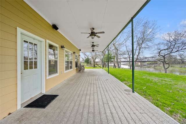 deck with a yard, ceiling fan, and a water view