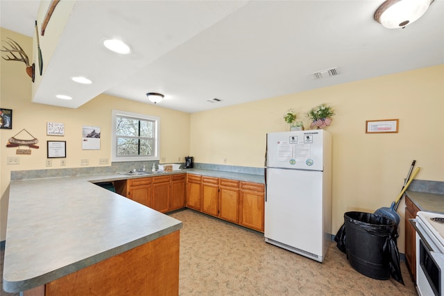 kitchen featuring light colored carpet, sink, white appliances, and kitchen peninsula