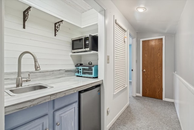 kitchen with sink, vaulted ceiling, light colored carpet, and fridge