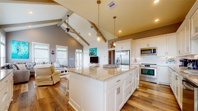 kitchen featuring a center island, stainless steel appliances, white cabinetry, and a wealth of natural light