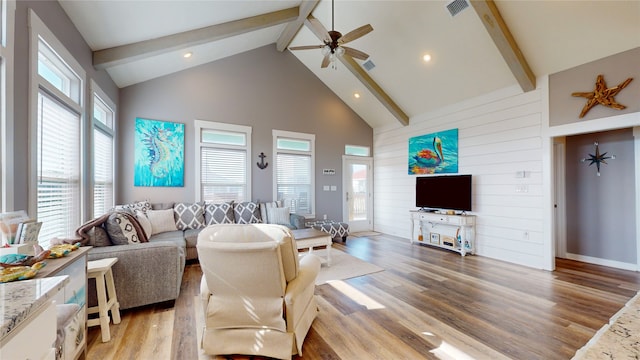 living room with plenty of natural light, high vaulted ceiling, light hardwood / wood-style floors, and beamed ceiling