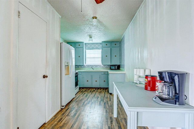 kitchen with white refrigerator with ice dispenser, blue cabinetry, stove, dark hardwood / wood-style flooring, and a textured ceiling