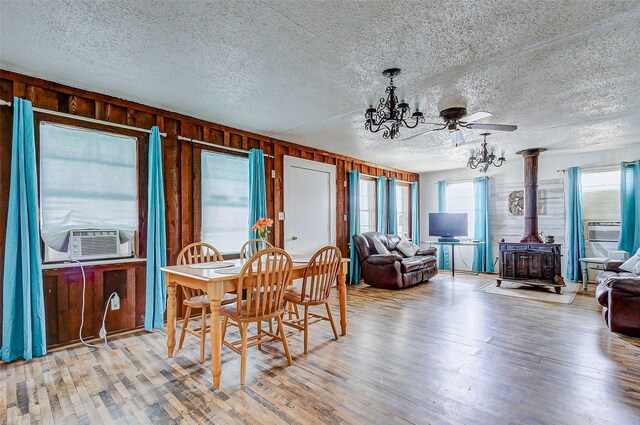 dining room with a wood stove, wooden walls, hardwood / wood-style flooring, and a textured ceiling