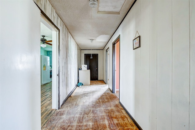 corridor with light hardwood / wood-style flooring and a textured ceiling