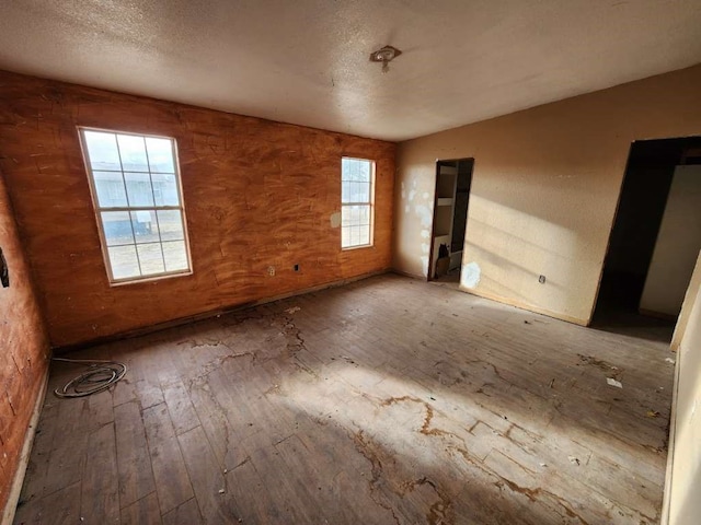 unfurnished bedroom featuring a textured ceiling, multiple windows, and hardwood / wood-style floors