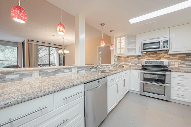 kitchen featuring white cabinets, decorative backsplash, light stone counters, stainless steel appliances, and a sink