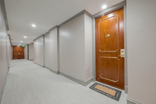 corridor with crown molding and light carpet