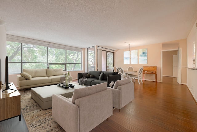 living room with a textured ceiling, a healthy amount of sunlight, a chandelier, and dark hardwood / wood-style flooring