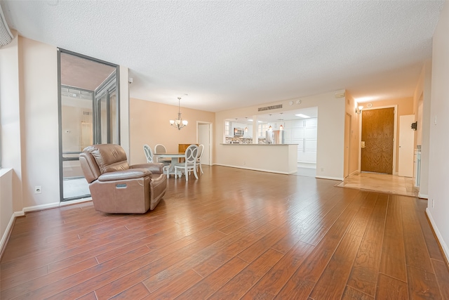 living room featuring a textured ceiling, a chandelier, and hardwood / wood-style floors