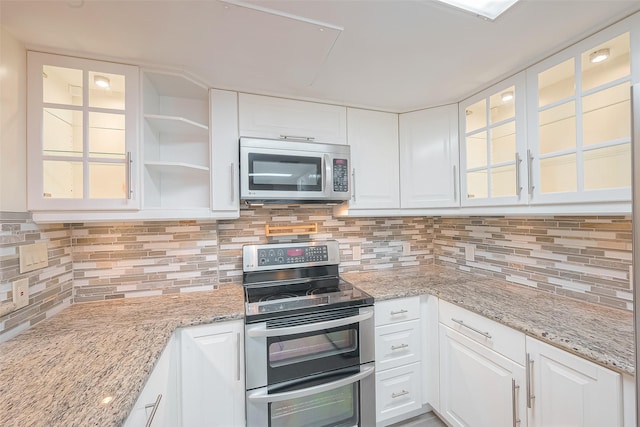 5150 Hidalgo St Unit 204, Houston, TX 77056 - kitchen with stainless steel appliances, white cabinets, backsplash, glass insert cabinets, and light stone counters