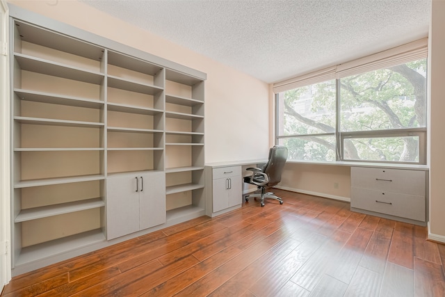 unfurnished office with hardwood / wood-style flooring and a textured ceiling