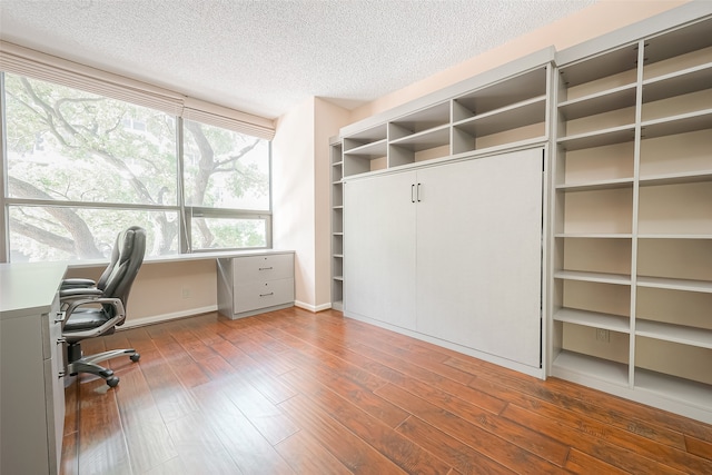 unfurnished office featuring hardwood / wood-style flooring and a textured ceiling