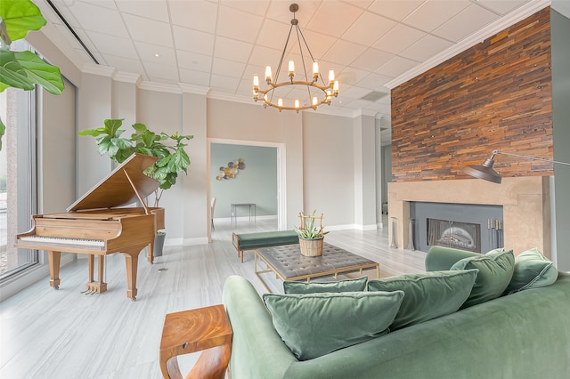 living room with wood-type flooring, a chandelier, ornamental molding, and a large fireplace