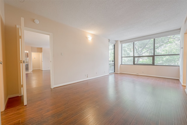 empty room with hardwood / wood-style floors and a textured ceiling