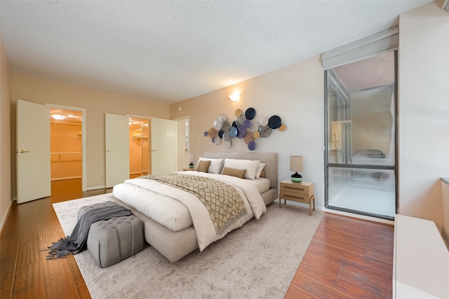 bedroom featuring hardwood / wood-style floors, a textured ceiling, a closet, and a walk in closet