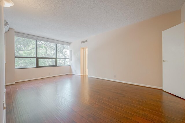 empty room featuring hardwood / wood-style flooring and a textured ceiling