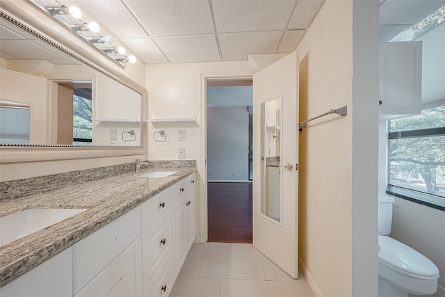 bathroom with a paneled ceiling, tile patterned floors, vanity, and toilet