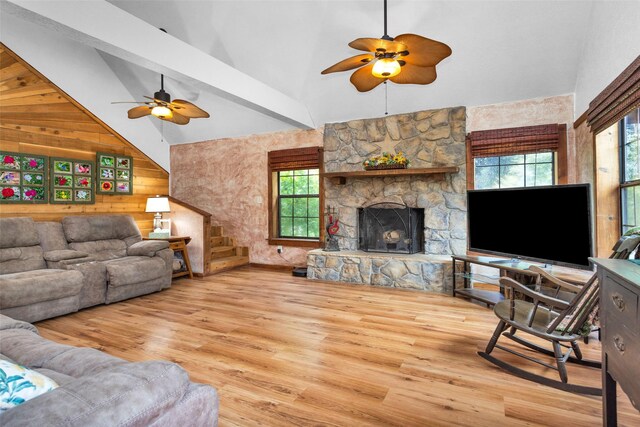 living room with light wood-type flooring, ceiling fan, and wooden walls