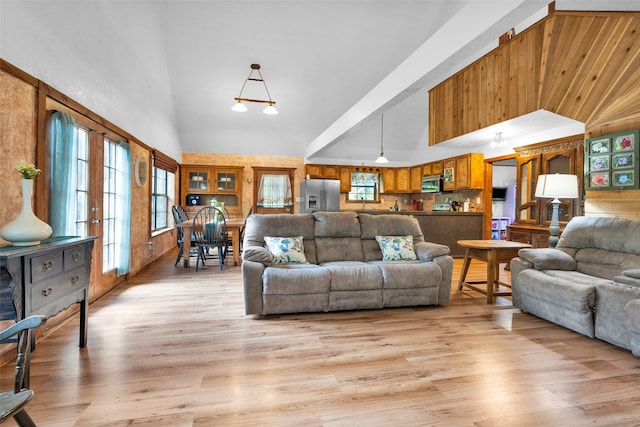 living room featuring high vaulted ceiling, french doors, and light hardwood / wood-style flooring