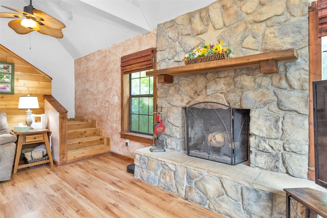 living room featuring hardwood / wood-style floors, a fireplace, lofted ceiling, wood walls, and ceiling fan