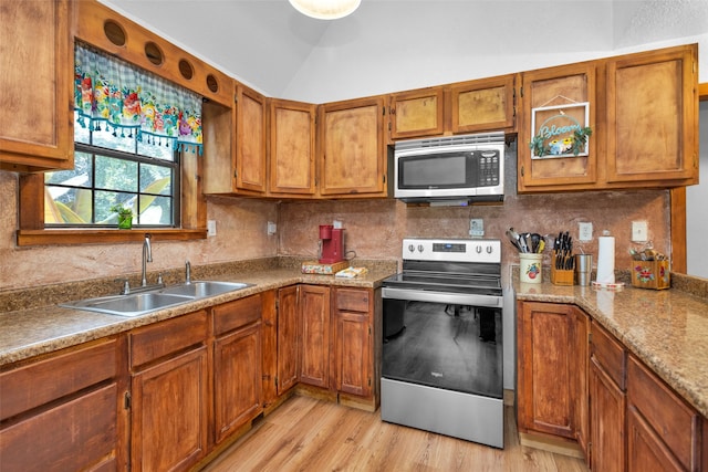 kitchen with appliances with stainless steel finishes, light hardwood / wood-style flooring, backsplash, and sink