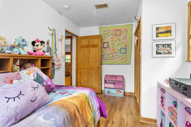 bedroom with light wood-type flooring and a textured ceiling