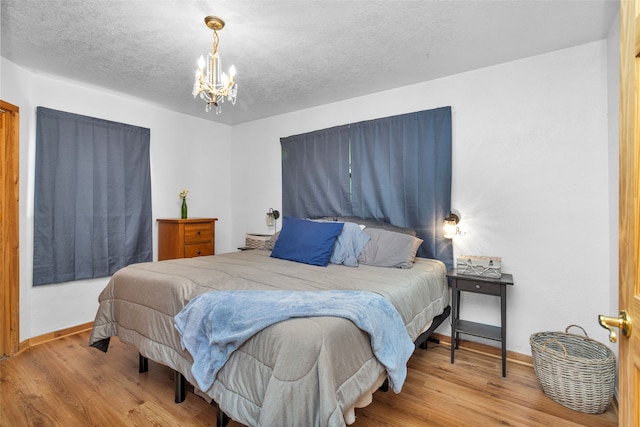 bedroom featuring light hardwood / wood-style flooring, a chandelier, and a textured ceiling