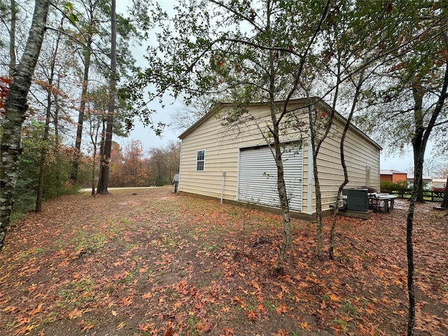 view of property exterior with a garage, central AC unit, and an outdoor structure