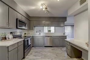 kitchen with sink, appliances with stainless steel finishes, track lighting, and gray cabinets